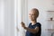 Happy bald cancer patient open curtains feeling good