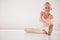 Happy ballet dancer girl stretching on the floor in a dance studio with mockup white background. Portrait ballerina kid