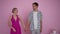 Happy Barbie and Ken standing at background of pink wall looking at each other taking hands turning looking at camera