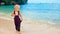 Happy barefoot child in loose jumpsuit on tropical sea beach