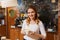 Happy barista woman with latte at coffee shop