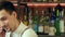 Happy barman in apron calling on smartphone at bar
