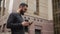 Happy beard young man texting on smartphone and drinking coffee in the street at sunset