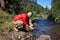 Happy bearded hiker is going to wash face in mountain river