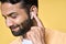 Happy bearded indian man wearing earbuds listening music or podcast. Closeup