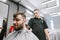 Happy bearded male client cutting hair in barber. Positive man makes a haircut in a barbershop. Professional barber