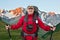 Happy bearded tourist with camera, Navigator and trekking poles on the background of beautiful mountains