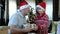 Happy beared senior man in red christmas hat with his grandson and gifts, celebrating new year