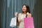 Happy and beautiful Asian Chinese woman walking on the street posing on background smiling cheerful carrying shopping bag