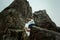 Happy beautiful bride and elegant stylish groom hugging on rock