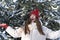 Happy beautiful brunette girl in red hat with bubo throws snow. Laughing young woman in snowy forest