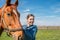 Happy beautiful brunette taking care of her brown horse