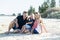 Happy beautiful Caucasian family having holidays on the beach smiling with mother and father sitting on sand with little son and y