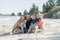 Happy beautiful Caucasian family having holidays on the beach smiling with mother and father sitting on sand with little son and y