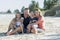 Happy beautiful Caucasian family having holidays on the beach smiling with mother and father sitting on sand with little son and y