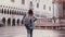 Happy beautiful Caucasian female tourist walking on San Marco square with pigeon sitting on arm in Venice slow motion.