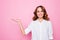 Happy beautiful cheerful smiling mature woman wearing formal shirt is holding her palm below empty space, isolated on bright pink