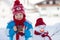 Happy beautiful child building snowman in garden, winter time, h