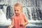 Happy beautiful child girl toddler portrait playing at waterfall cascade during summer vacation concept happy childhood lifestyle