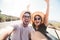 Happy beautiful couple in love taking a selfie portrait driving a convertible car on the road at vacation