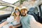 Happy beautiful couple in love taking a selfie portrait driving a convertible car on the road at vacation. Rental cars