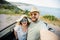 Happy beautiful couple in love taking a selfie portrait driving a convertible car on the road at vacation. Rental cars