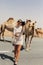 A happy beautiful girl, smiling, takes a selfie with a camel by the road during a trip to the desert, Dubai, UAE