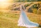 happy beautiful joyful bride walking in hills, long train white dress back rear view mystery silhouette,no face. Girl