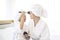 Happy beautiful mom and daughter in white bathrobe applying natural Make-Up with cosmetic powder brush, Family and Beauty Concept