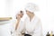 Happy beautiful mom and daughter in white bathrobe applying natural Make-Up with cosmetic powder brush, Family and Beauty Concept