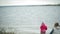 Happy and beautiful mother and daughter are feeding gulls on the beach on the river bank