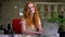 Happy beautiful smile of caucasian ginger girl, sitting at her desktop and using laptop during work, being self-employed