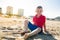 Happy beautiful smiling child sitting at the sand beach, look at camera