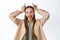 Happy beautiful teenage girl showing bull horns gesture, smiling and looking daring, standing against white background