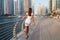 Happy beautiful unrecognizable tourist woman in fashionable summer white dress enjoying in Dubai marina in United Arab Emirates.