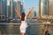 Happy beautiful unrecognizable tourist woman in fashionable summer white dress enjoying in Dubai marina in United Arab Emirates.