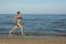 and happy beautiful woman in bikini running on the beach. In a cap with the inscription queen. Film effect.