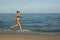 and happy beautiful woman in bikini running on the beach. In a cap with the inscription queen. Film effect.