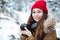 Happy beautiful woman photograher taking photos in winter forest