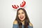 Happy beautiful woman with reindeer horns on her head looks at camera on white background. Christmas holidays.