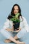 Happy beautiful woman with vitiligo sitting with potted plant in hands