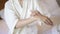 Happy beautiful woman in white bathrobe applying body moisturizing cream in bedroom, skin care and treatment concept