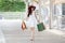 Happy beautiful young asian woman wearing white dress and sunglasses ,red hat with shopping bags over mall enjoying on street in