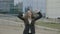Happy beautiful young businesswoman wearing office outfit dancing joyfully in nature in front of the corporation -