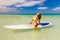 Happy beautiful young girl with paddle board on a tropical beach