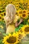 A happy, beautiful young girl in a yellow dress is standing in a large field of sunflowers. Summer time.