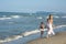 Happy beautiful young mom and child walk far away along the sea