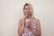 Happy beautiful young woman in a trendy pink summer sundress  with a tasty milkshake stands near the vintage wall in the city.