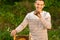 Happy beekeeper spends time in apiary. He holds a honeycomb full of bees. One hand is all in the bees