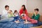 Happy big family is having fun together in bedroom. Large family morning concept. Four kids with parents wear pajamas drink tea in